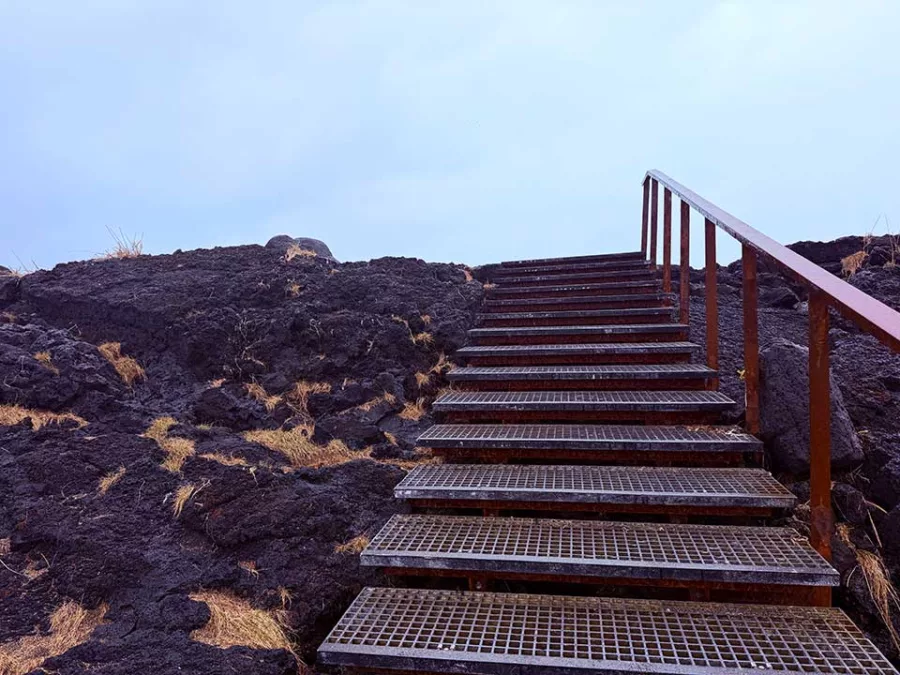 Metal stairs leading across black lava rock toward the Brimketill viewpoint