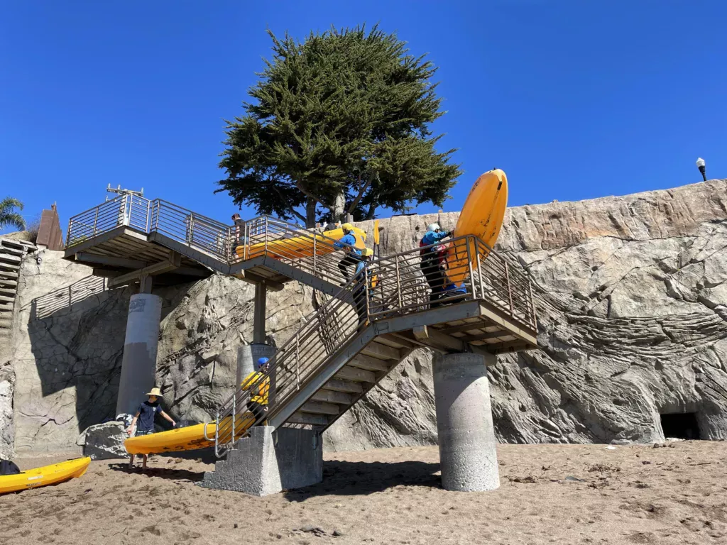 kayakers carrying their equipment down stairs to the beach